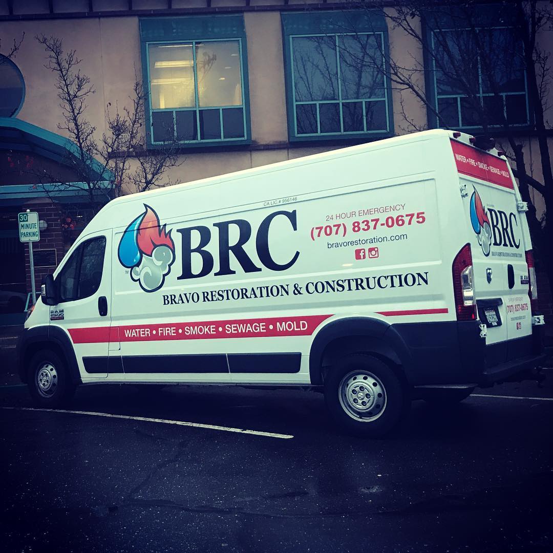 Brc restoration construction van, specializing in fire and smoke damage remediation, parked in front of a building.